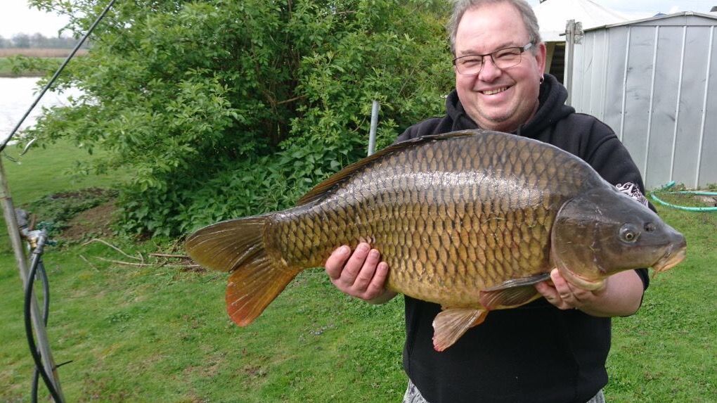 Mann hält einen geangelten Fisch hoch